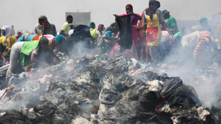 People try to salvage items from the burned down secondhand clothing market at Kantamanto in Accra, Ghana, on January 2, 2025. The fire at the Kantamanto market began in the early morning hours, destroying a large part of the area and displacing thousands of traders. AFP - NIPAH DENNIS