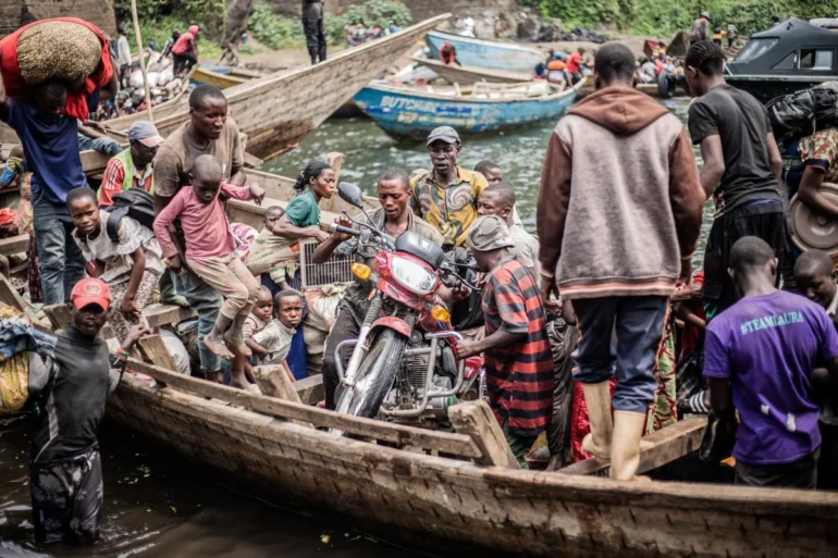 Congolese displaced fleeing the area of Minova board with their belongings boat leaving the port of Nzulo on January 21, 2025 to seek shelter in Goma. Photo by JOSPIN MWISHA/AFP via Getty Images.